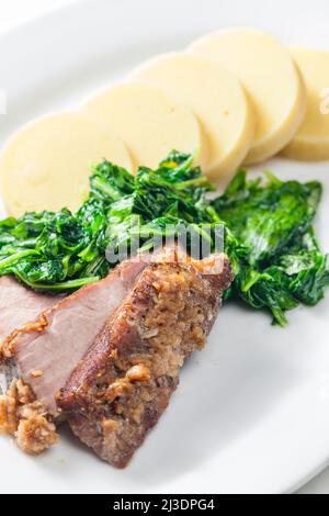 Schweinefleisch mit Knoblauch, dazu Spinat und Kartoffelknödel Stockfoto