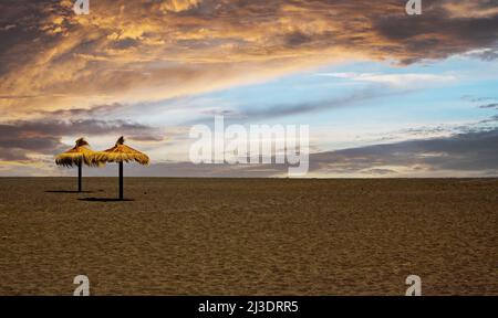 Blick auf verlassenen tropischen Sandstrand mit zwei Sonnenschirmen, Sturmwolken - Frühbuchertarif Konzept Stockfoto