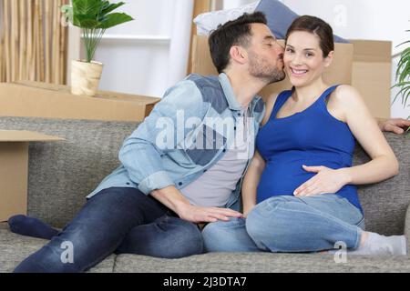 Mann küsst seine Schwangere auf der Couch Stockfoto