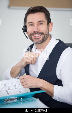 Mann trägt ein Headset und blättert durch den Ordner Stockfoto