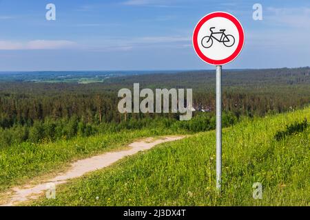 Keine Fahrräder. Rundes Verbotsschild an der Stange in der Nähe der Landstraße, die den Hügel hinunter führt Stockfoto