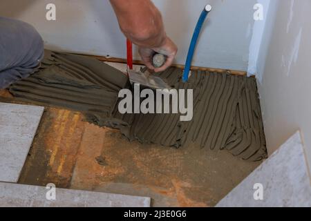 Arbeiter, der Fliesenkleber auf den Boden aufklebt Stockfoto