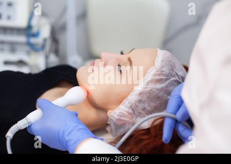 Frau, die eine Ultraschall-Gesichtsmassage auf einem Ultraschallgerät erhält. Stockfoto