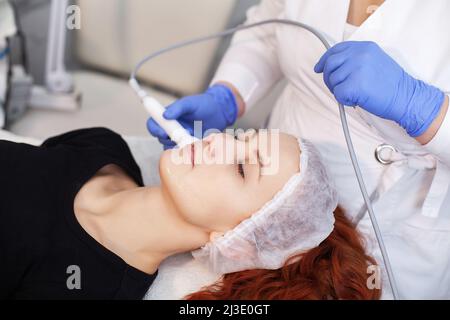 Frau, die eine Ultraschall-Gesichtsmassage auf einem Ultraschallgerät erhält. Stockfoto