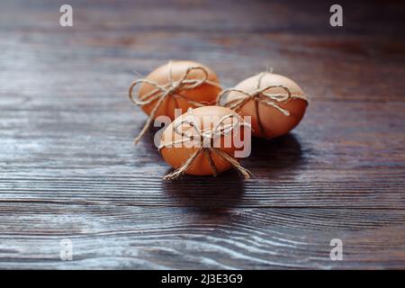 Osterbeige Eier schmücken mit Seil auf braunem Holzhintergrund mit Copyspace Stockfoto