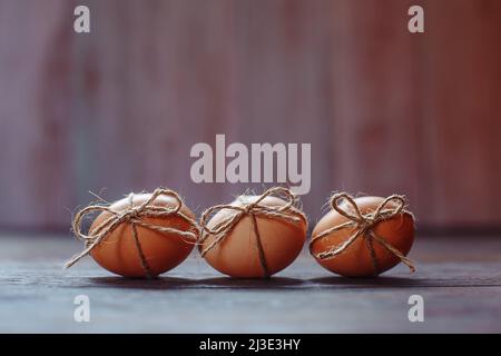 Osterbeige Eier schmücken mit Seil auf braunem Holzhintergrund mit Copyspace Stockfoto