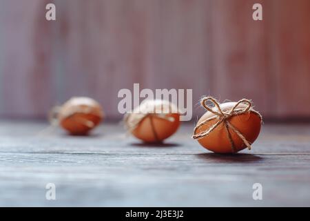 Osterbeige Eier schmücken mit Seil auf braunem Holzhintergrund mit Copyspace Stockfoto