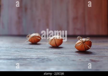 Osterbeige Eier schmücken mit Seil auf braunem Holzhintergrund mit Copyspace Stockfoto