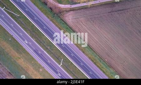 Luftaufnahme Sonnenaufgang von Wiesen und elektrischen Windmühlen über Hochgeschwindigkeitsautobahn am Morgen unter einem bunten Himmel natürliche Landschaft über der Panoramalandschaft. Hochwertige Fotos Stockfoto