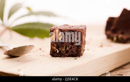 Marihuana-Brownie mit Marihuana-Blättern, Dessert auf Holztisch. Stockfoto