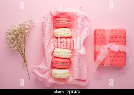 Makkaroni in einer Schachtel auf hellrosa Hintergrund mit weißen Blüten, Flatlays Stockfoto