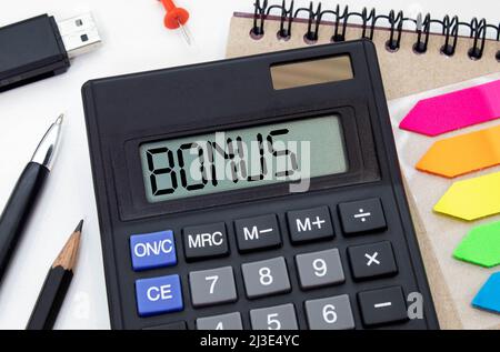 WORTBONUS auf der Anzeige eines Rechners über Finanzdokumente. Stockfoto