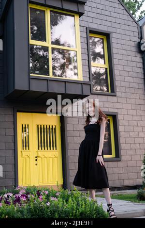 Junge Brünette Frau in der Nähe von modernen Gebäude, neues Zuhause. Hauswarming. Kauf ein Haus. Glücklich unbeschwertes Leben in Privathaus. Stockfoto