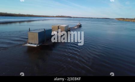 Containerschiff segelt auf einem breiten schönen Fluss auf Sonnenuntergang Himmel Hintergrund. Clip. Konzept des Transports, Luftaufnahme. Stockfoto