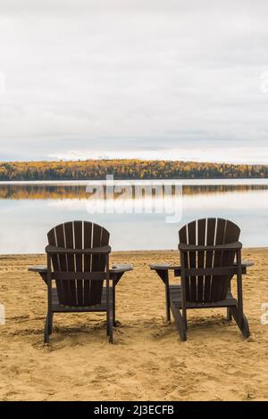 Braune Adirondack-Stühle am Strand mit Blick auf den Lac Taureau im Herbst, Saint-Michel-des-Saints, Lanaudiere, Quebec, Kanada. Stockfoto