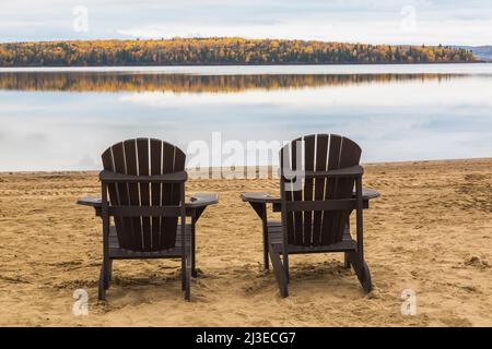 Braune Adirondack-Stühle am Strand mit Blick auf den Lac Taureau im Herbst, Saint-Michel-des-Saints, Lanaudiere, Quebec, Kanada. Stockfoto