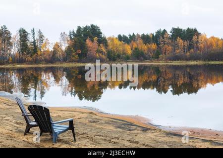 Braune Adirondack-Stühle am Strand mit Blick auf den Lac Taureau im Herbst, Saint-Michel-des-Saints, Lanaudiere, Quebec, Kanada. Stockfoto