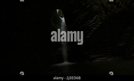 Erstaunlich schöner Wasserfall in tiefer Höhle im chinesischen Nationalpark. Kreativ. Kleiner Wasserfall in einer dunklen unterirdischen Höhle. Stockfoto