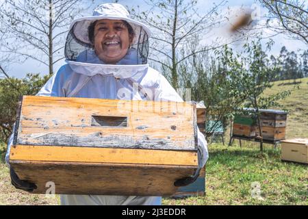 Porträt einer Imkerin, die eine Wabe mit Bienen trägt. Honigernte-Konzept Stockfoto