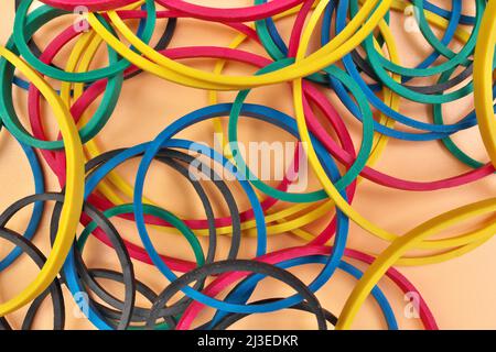 Vollformat-Bild-Flatlay von mehrfarbigen elastischen Gummibändern auf einem fröhlichen Orange Pastell Hintergrund Stockfoto