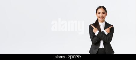 Gut aussehende asiatische Verkäuferin schlagen zwei Möglichkeiten vor. Attraktive Geschäftsfrau in schwarzem Anzug zeigt Finger seitlich, haben nur wenige Varianten, helfen zu machen Stockfoto