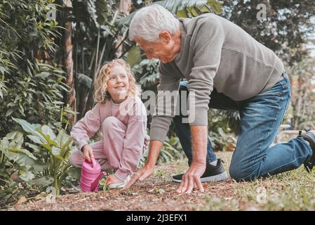 Der Schlamm wäscht sich weg, aber die Erinnerungen bleiben für immer bestehen. Aufnahme eines entzückenden kleinen Mädchens, das mit ihrem Großvater im Garten arbeitet. Stockfoto