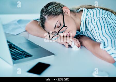 Sie arbeitete die ganze Nacht. Aufnahme einer müde aussehenden jungen Geschäftsfrau, die tagsüber im Büro auf ihrem Schreibtisch schläft. Stockfoto