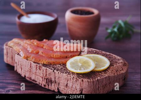 Geräucherte Lachsfilets mit Zitrone, Salz und Pfeffer auf Schneidebrett Stockfoto