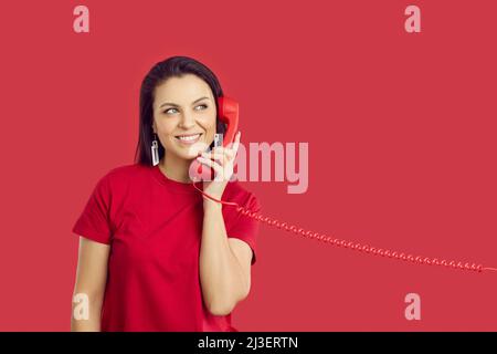 Lächelnde Frau spricht über das Festnetztelefon Stockfoto