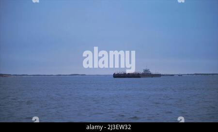 Barge schwimmt am bewölkten Tag auf dem Fluss. Clip. Schöne Flusslandschaft mit schwimmenden Handelsschiff. Barge überqueren auf dem Fluss an bewölktem Tag Stockfoto