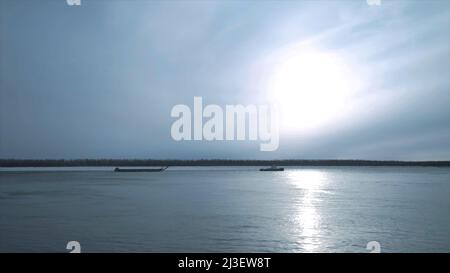 Barge schwimmt am bewölkten Tag auf dem Fluss. Clip. Schöne Flusslandschaft mit schwimmenden Handelsschiff. Barge überqueren auf dem Fluss an bewölktem Tag Stockfoto