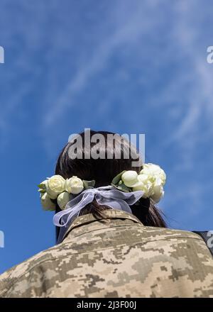 Kiew, Ukraine. 07. April 2022. Junge Frau in militärischer Tarnuniflorme und einem Rosenkranz vor blauem Himmel. Mitglieder der Kiewer Territorialverteidigung, Anastasiia Mokhina, 24 Jahre alt, und Viacheslav Hohljuk, 43 Jahre alt, Verheiratet heute nach den Gesetzen des Kriegsrechts in Kiew, Ukraine. Kredit: SOPA Images Limited/Alamy Live Nachrichten Stockfoto