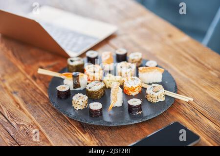 Steinplatte mit Sushi auf Holztisch Stockfoto
