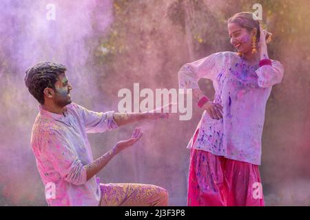 Fröhliches indisches junges Paar, das beim Holi-Festival tanzt Stockfoto