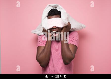 Afrikanischer Mann, der wütend schrie und ein Kissen in der Hand hielt Stockfoto