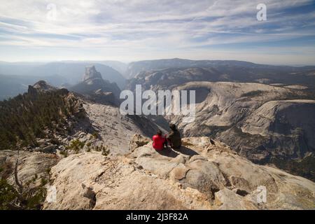 Pärchen sitzen auf dem Gipfel der Wolken Rast Hike mit Half Dome View, Yosemite National Park. Stockfoto
