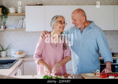 Glückliches Seniorenpaar, das zu Hause zusammen kocht. Stockfoto