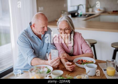 Glückliches Seniorenpaar, das zu Hause zusammen zu Abend gegessen hat. Stockfoto