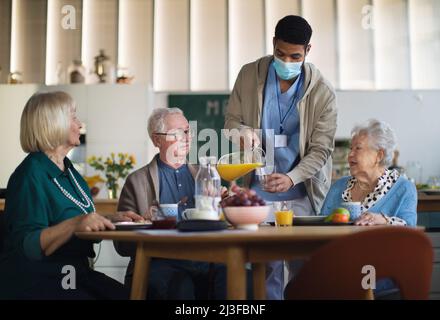 Eine Gruppe von fröhlichen Senioren, die im Pflegeheim frühstücken. Stockfoto