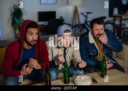 Nervöse Fußballfans Freunde, die zu Hause ein Fußballspiel live im Fernsehen sehen Stockfoto