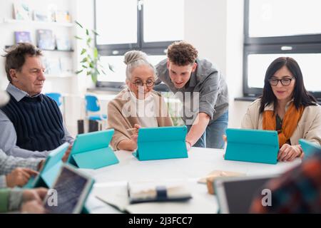 Gruppe von Senioren, die mit dem Lehrer an DER IT-Klasse im Gemeindezentrum teilnehmen Stockfoto