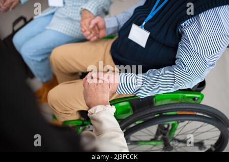 Nahaufnahme eines älteren Mannes, der bei der Gruppentherapie im Rollstuhl sitzt. Stockfoto
