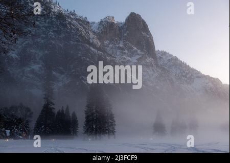 Das Yosemite Valley ist von einer dünnen Nebelschicht umgeben, die über dem merced River hängt und eine unheimliche Atmosphäre beim Sonnenuntergang bietet. Stockfoto