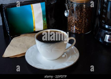 Kaffeemaschine, eine Tasse, ein Glas voller Kaffeebohnen und ein Löffel Filterkaffee. Stockfoto