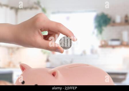 Russische Rubel-Münzen in ein Sparschwein stecken. Das Konzept der Rettung des russischen Rubels Stockfoto