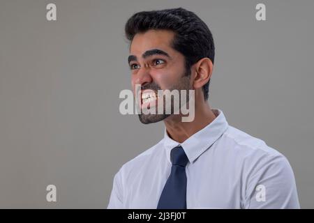 Porträt eines wütenden jungen Mannes in weißem Hemd, der mit klemmenden Zähnen davonschaut Stockfoto