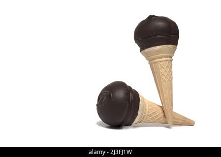 Nahaufnahme von zwei süßen Eisbecher-Kegeln auf weißem Hintergrund, beide mit gekreuzter Schokolade überzogen und mit Zuckerschaum gefüllt Stockfoto