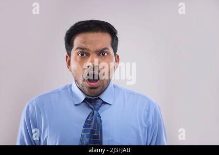 Porträt eines überraschten Geschäftsmannes, der mit geöffnetem Mund die Kamera ansah Stockfoto