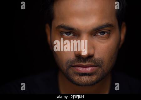 Nahaufnahme eines ernsthaften jungen Mannes vor dunklem Hintergrund Stockfoto