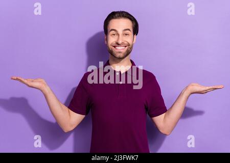 Foto des optimistischen Millennial Brunet Kerl halten promo tragen violette T-Shirt isoliert auf lila Farbe Hintergrund Stockfoto